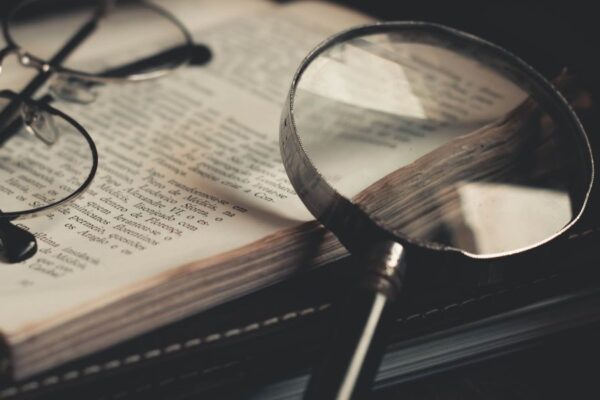 Boek met daarop een bril en vergrootglas