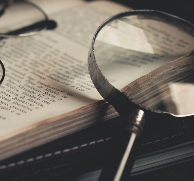 Boek met daarop een bril en vergrootglas