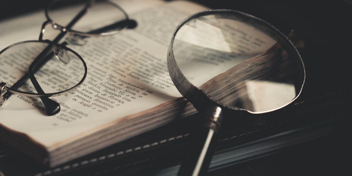 Boek met daarop een bril en vergrootglas